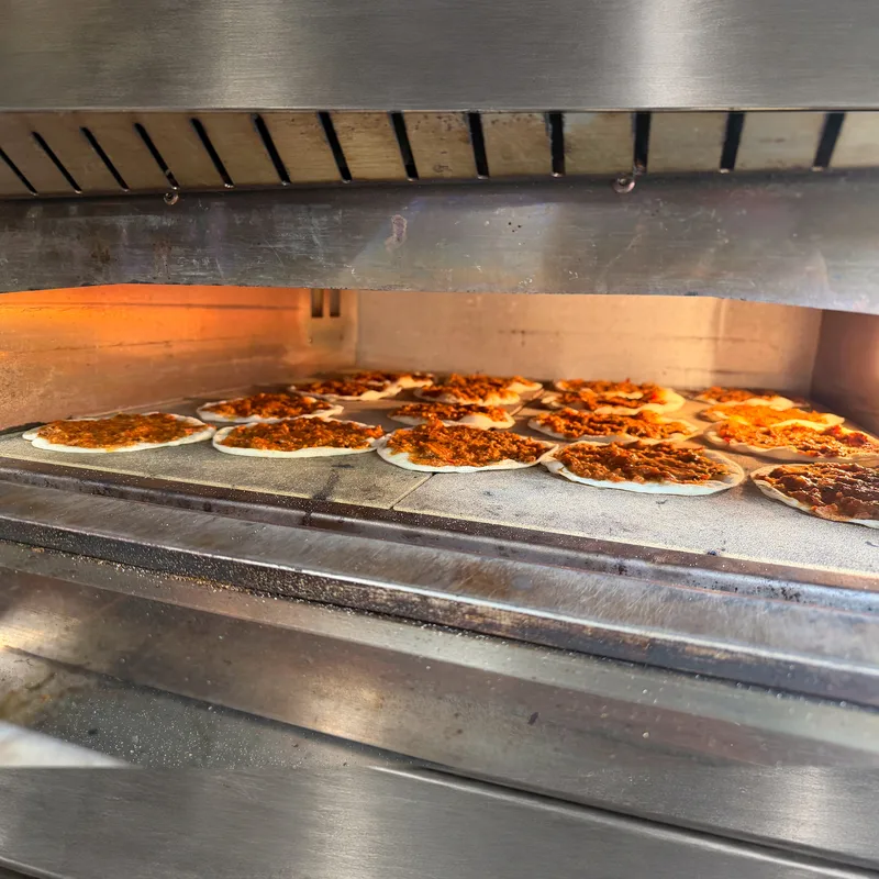 Mehrere Lahmacun backen nebeneinander im offenen Steinofen