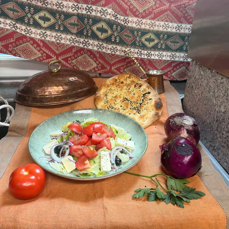 Salatteller mit Tomaten, Zwiebeln, Käse und Fladenbrot auf einem Tuch