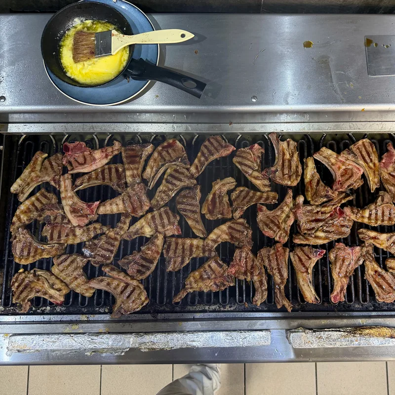 Viele Lammkoteletts mit Grillspuren auf einem Küchengrill