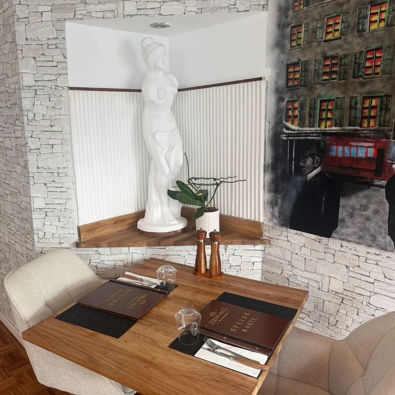 Gedeckter Sitzplatz mit weisser Skulptur und Wandgemälde
