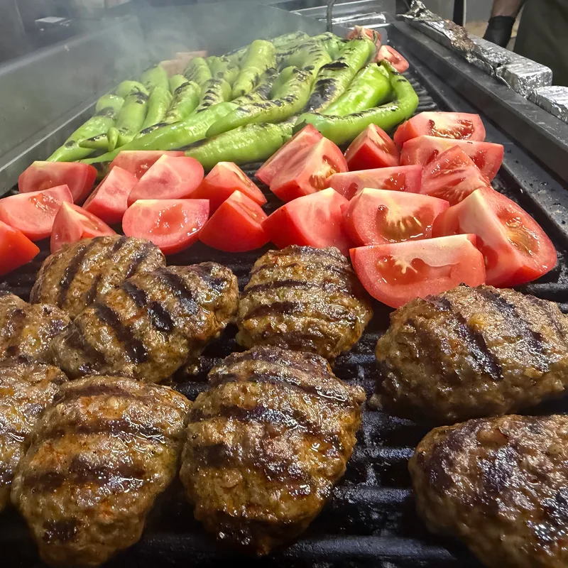 Köfte, Tomaten und grüne Peperoni liegen auf dem Grill