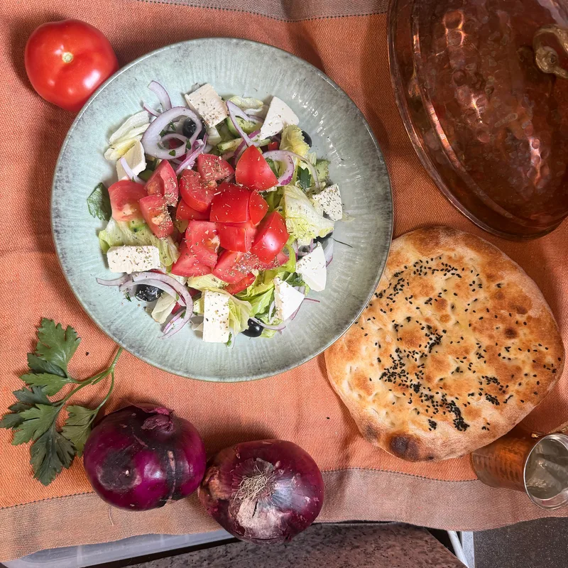 Salatteller mit Tomaten, Käse, Zwiebeln und Fladenbrot von oben