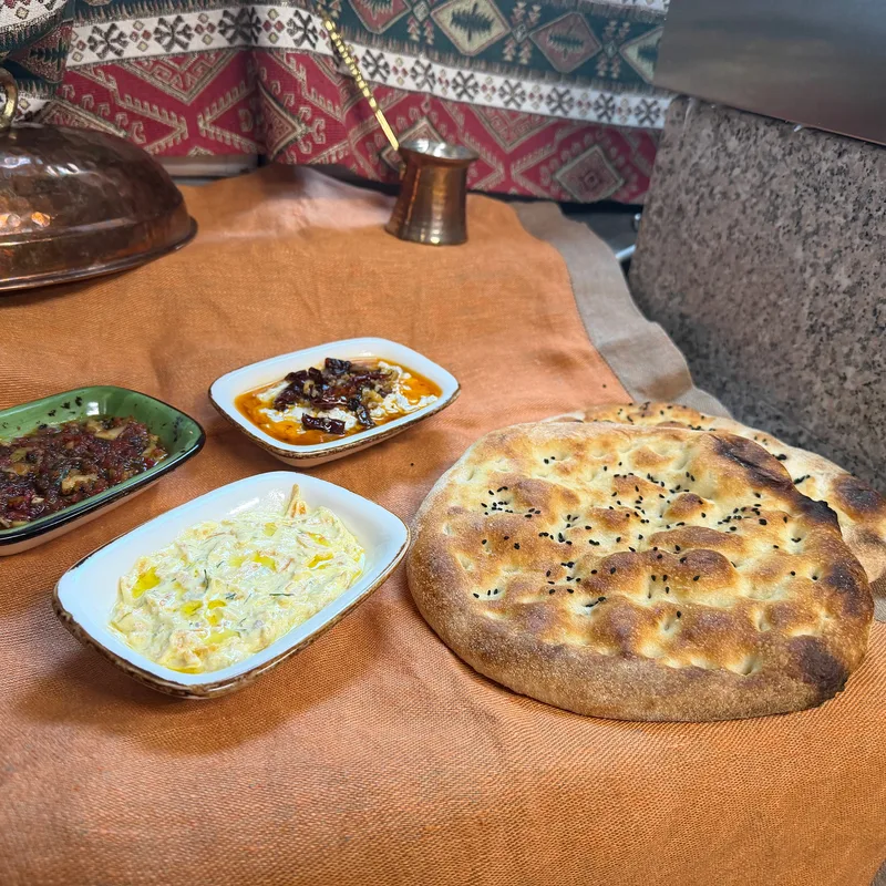 Frisches Fladenbrot mit Joghurt-Dip und Meze auf einem Tuch