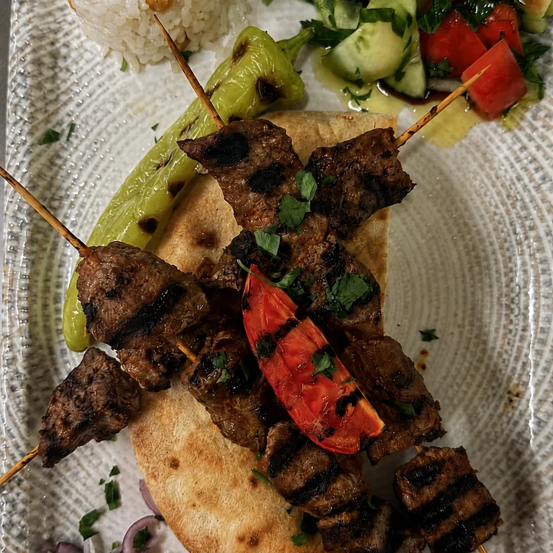 Fleischspiesse auf Fladenbrot mit Reis, Salat und gegrillter Peperoni