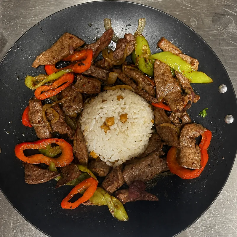 Rindfleischstreifen mit Paprika und Peperoni um einen Reisberg in der Pfanne