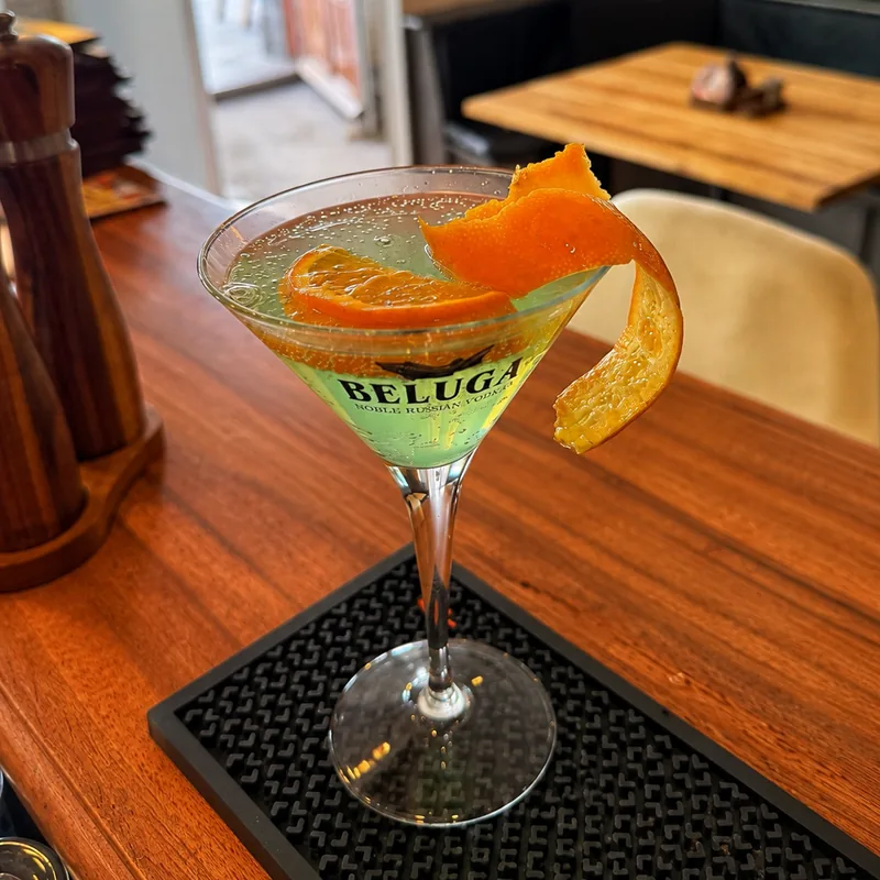 Cocktail im Martiniglas mit Orangenzeste an der Bar